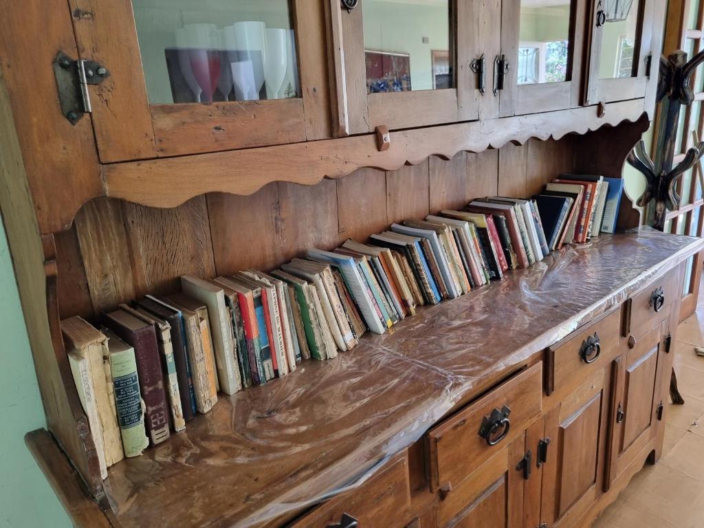 a wooden cabinet filled with lots of books at Chácara Áquila in São Roque