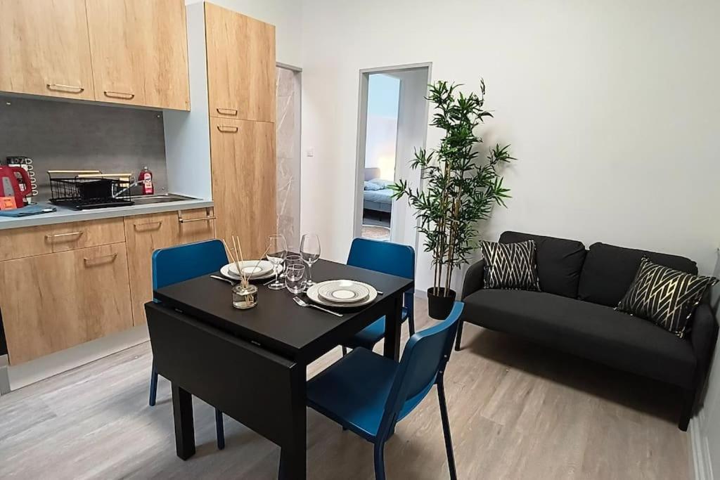 ein Wohnzimmer mit einem schwarzen Tisch und blauen Stühlen in der Unterkunft - Meublés de Beaulieu cœur de ville - in Angoulême