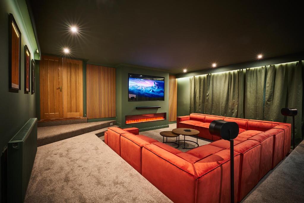 a living room with a red couch and a flat screen tv at The Old Stables - Hot Tub, Sauna and Cinema in Alyth