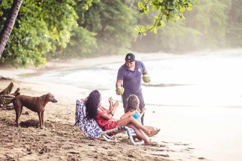 a group of people sitting on a beach with a dog at Tree House Beachfront Lodge in Puerto Viejo