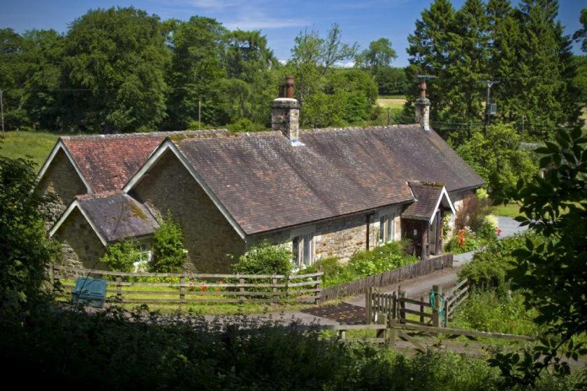 una antigua casa de piedra con techo de metal en Garden Cottage Haughton Castle 2 en Hexham