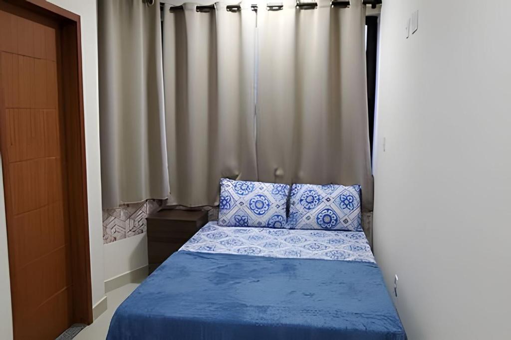 a bed with blue and white pillows in a bedroom at Apartamento em São Pedro, prédio novo 402 in Juiz de Fora