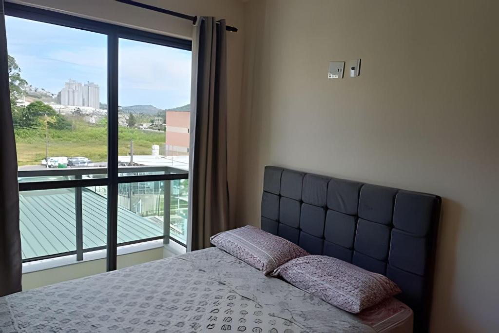 a bedroom with a bed and a large window at Apartamento em São Pedro 305 in Juiz de Fora