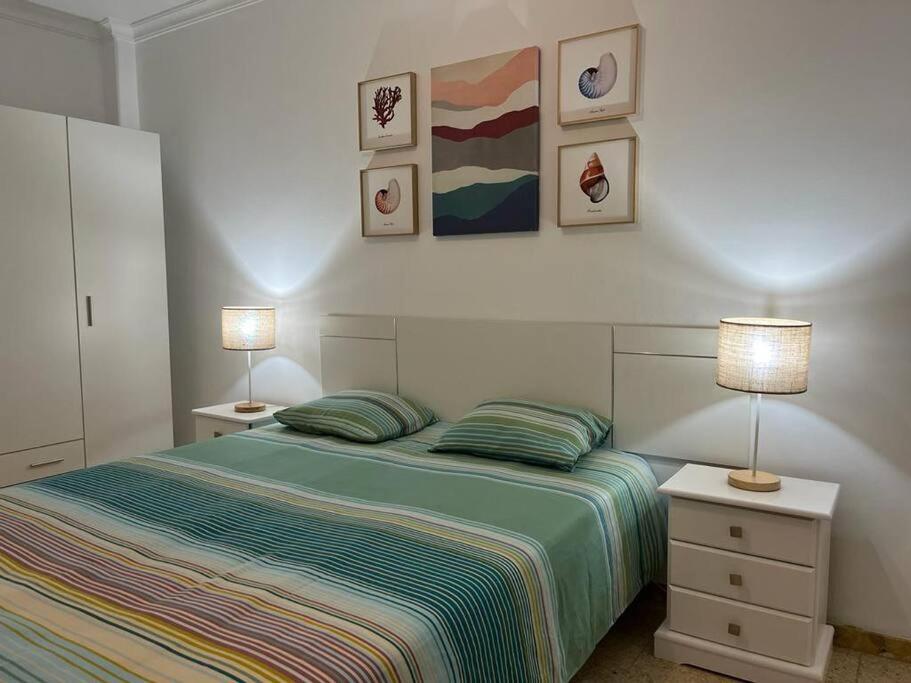 a bedroom with a bed with two lamps and pictures on the wall at Pieds dans l'eau - vue sur mer - Playa de Melenara in Melenara