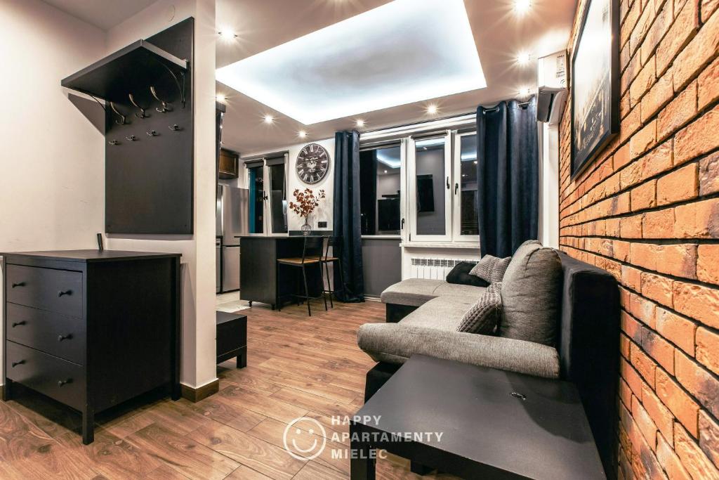 ein Wohnzimmer mit Sofa und Ziegelwand in der Unterkunft Happy - Happy Apartamenty Mielec in Mielec