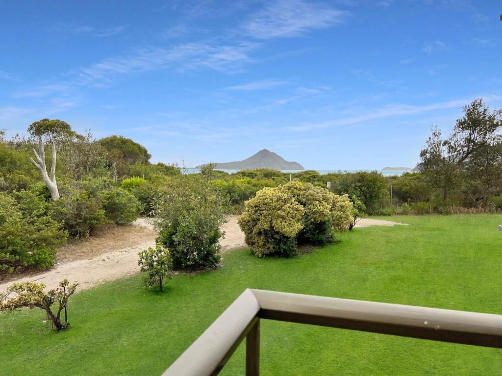 a view from a balcony of a yard with a mountain in the background at Foreshore Paradise Nelson Bay in Nelson Bay