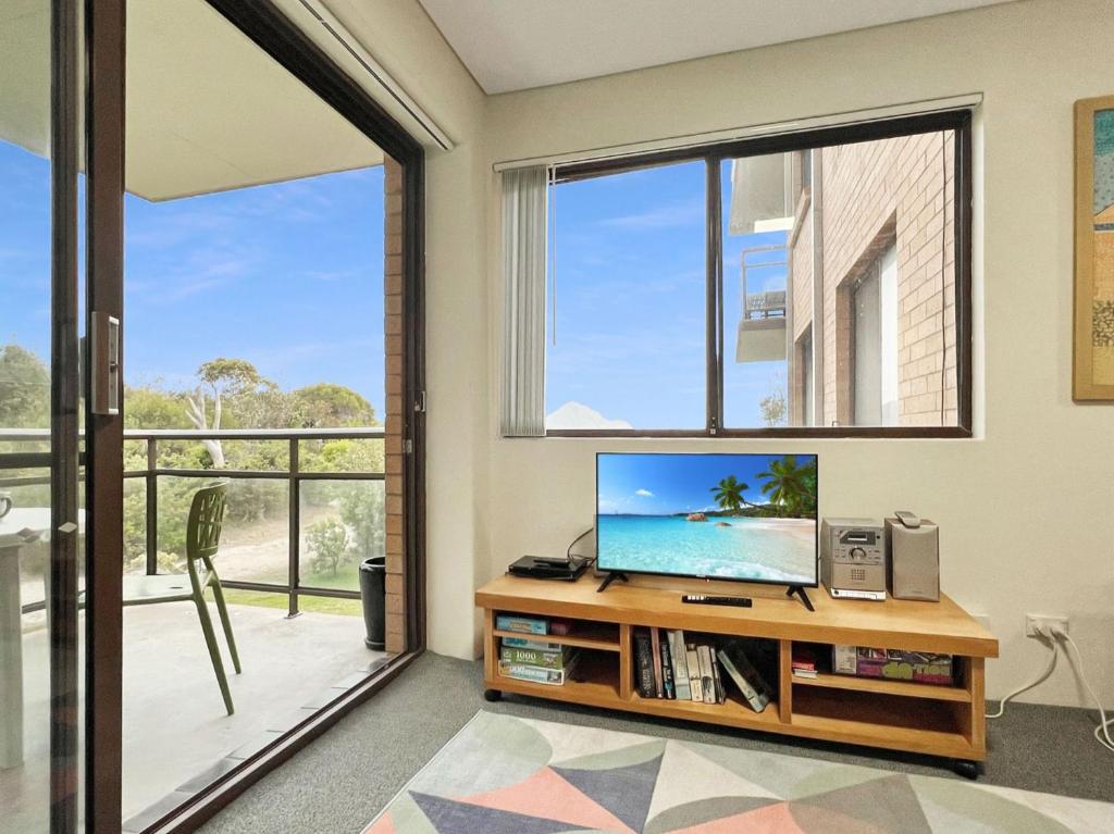 a living room with a tv and a large window at Foreshore Paradise Nelson Bay in Nelson Bay