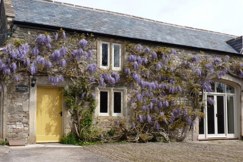 a building with purple flowers on the side of it at Manor Coach House in Farrington Gurney