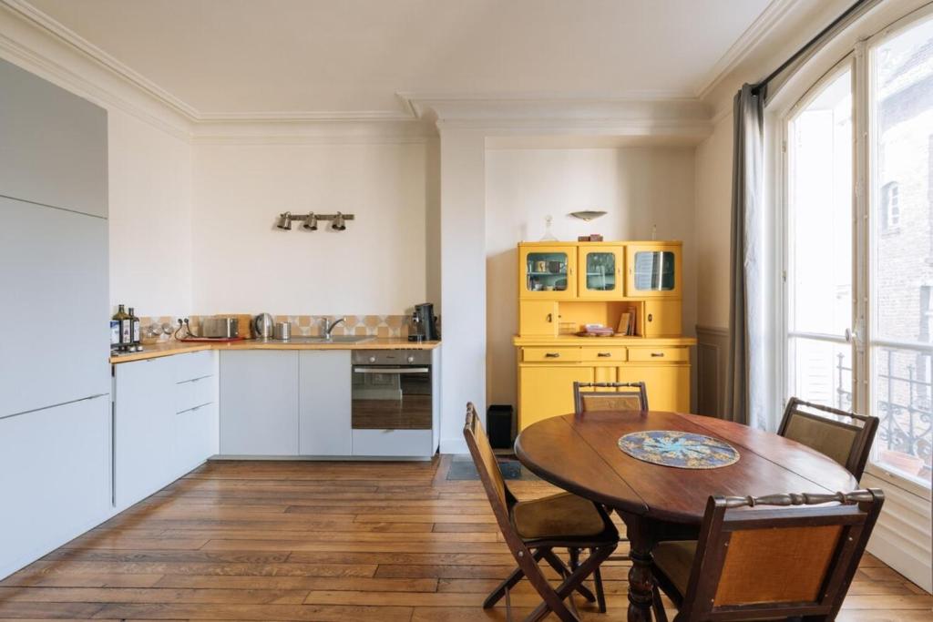 パリにあるLuminous Parisian-style 1BD ApartmentBellevilleのキッチン(木製テーブル付)、ダイニングルーム