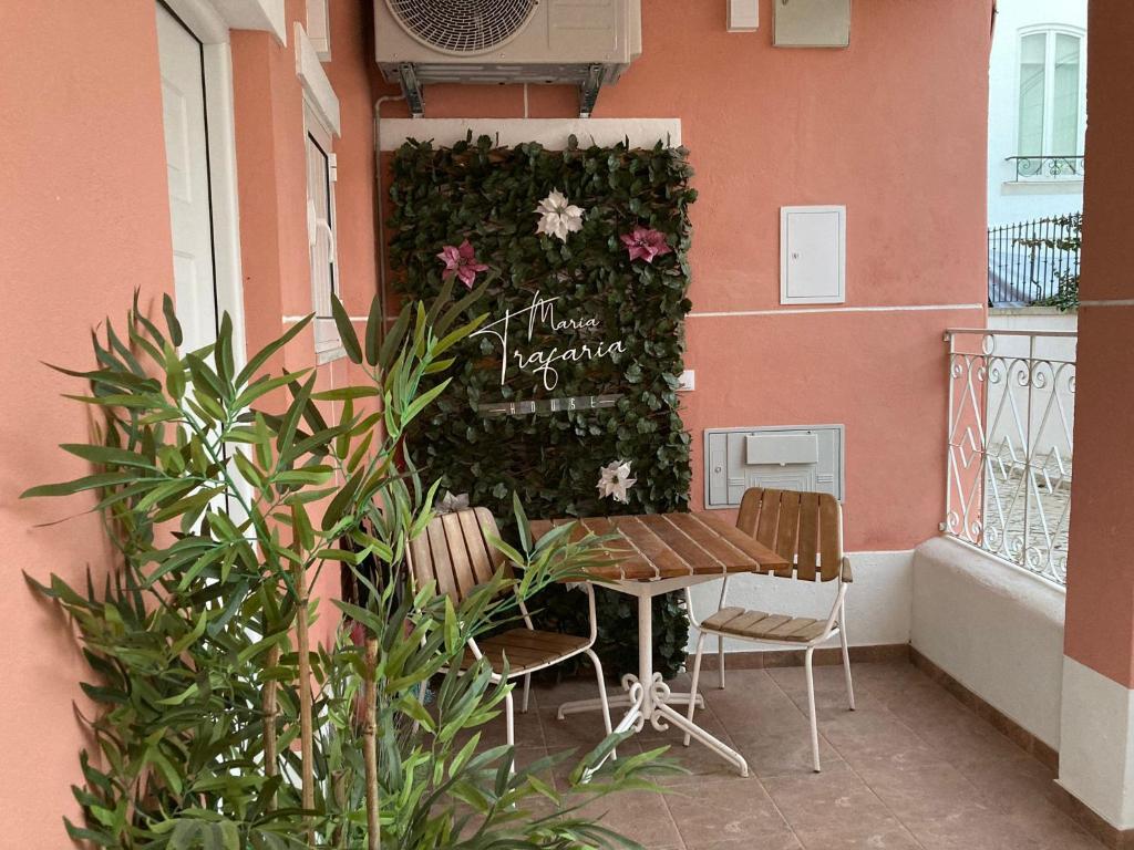 a table and chairs on a balcony with a wall with flowers at Maria Trafaria House in Trafaria