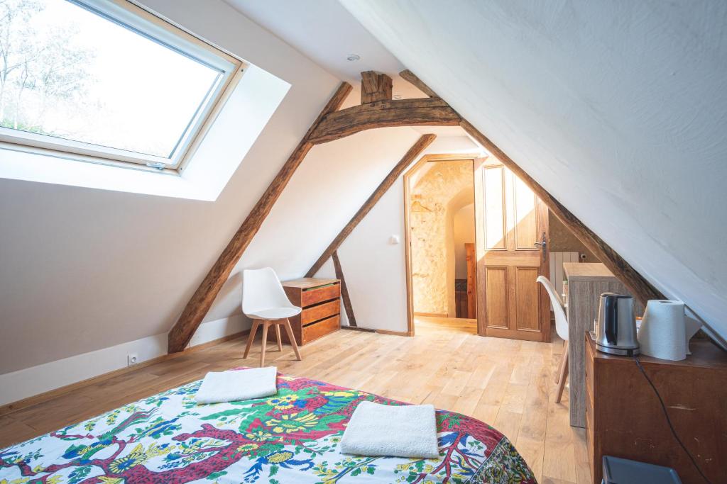 a attic bedroom with a bed and a window at Domaine Moulin de Boiscorde 1h45 Paris in Rémalard en Perche