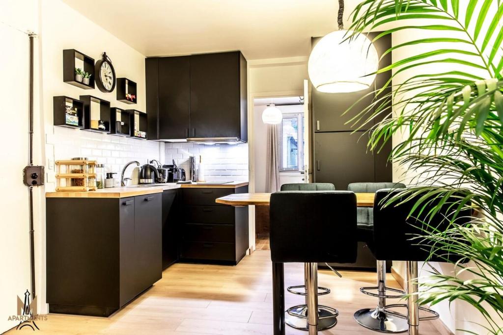 une cuisine avec des armoires noires et une table avec des chaises dans l'établissement Montmartre superbe moderne appartement 4 personnes, à Paris