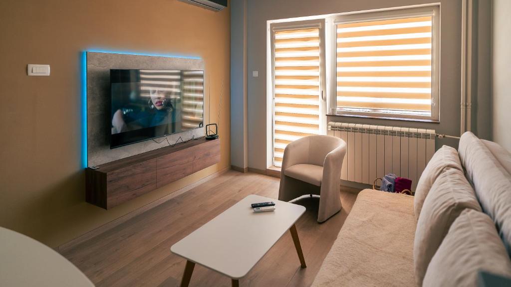 Una sala de estar con un sofá y un televisor. en Riverside Retreat, en Skopje