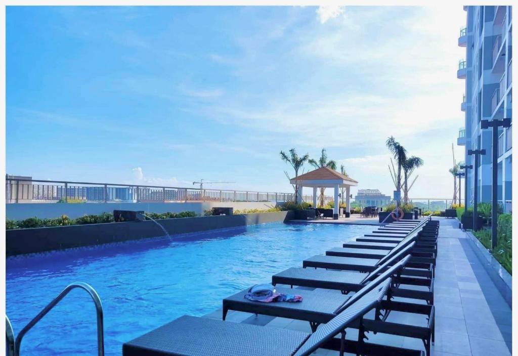 una piscina con una fila de mesas y bancos en Manila Bay Retreat at Soleil Suite, en Manila