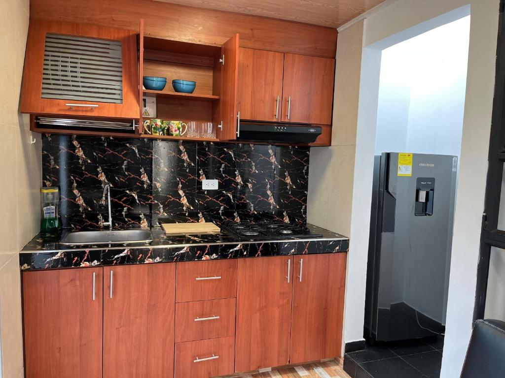 uma cozinha com armários de madeira e bancadas de mármore preto em Apartamento en Normandia a 10 minutos del aeropuerto em Bogotá