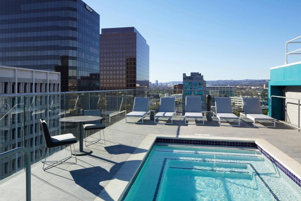 a rooftop pool with chairs and a table on a building at AC Hotel by Marriott Beverly Hills in Los Angeles
