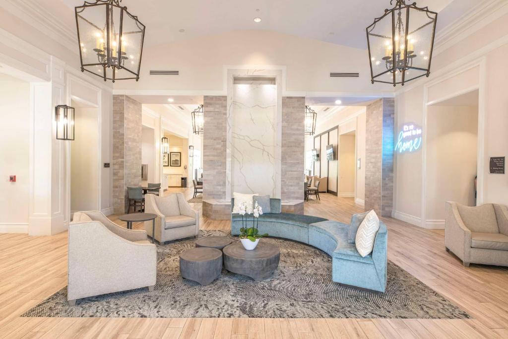 sala de estar con sofá azul y sillas en Homewood Suites by Hilton Palm Beach Gardens, en Palm Beach Gardens