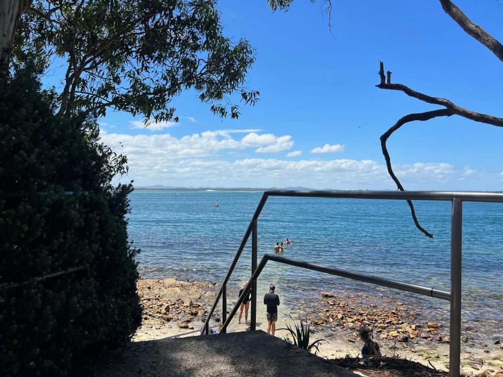 a man standing on a beach near the water at Foreshore Paradise Nelson Bay in Nelson Bay