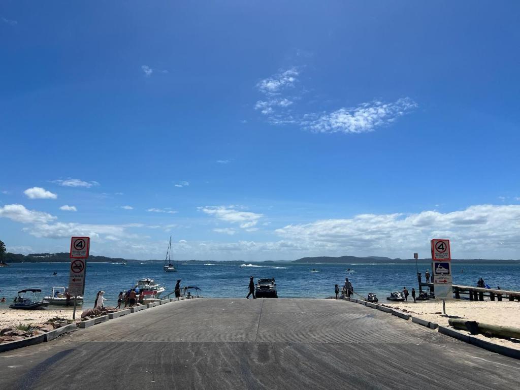 a road next to a beach with the ocean at Foreshore Paradise Nelson Bay in Nelson Bay