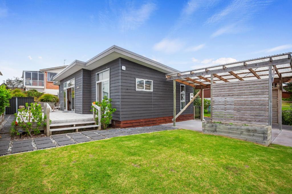 a gray house with a lawn in front of it at Relax on Dillon - Waihi Beach Holiday Home in Waihi Beach