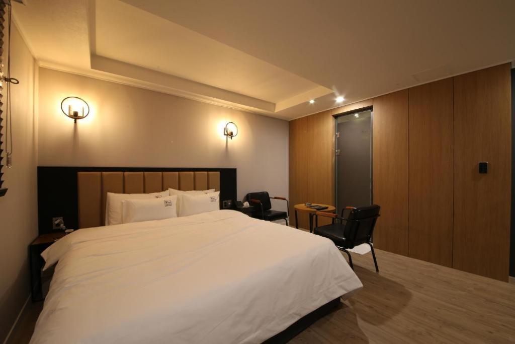 a bedroom with a large white bed and two chairs at No.25 Hotel Busan Seomyeon in Busan