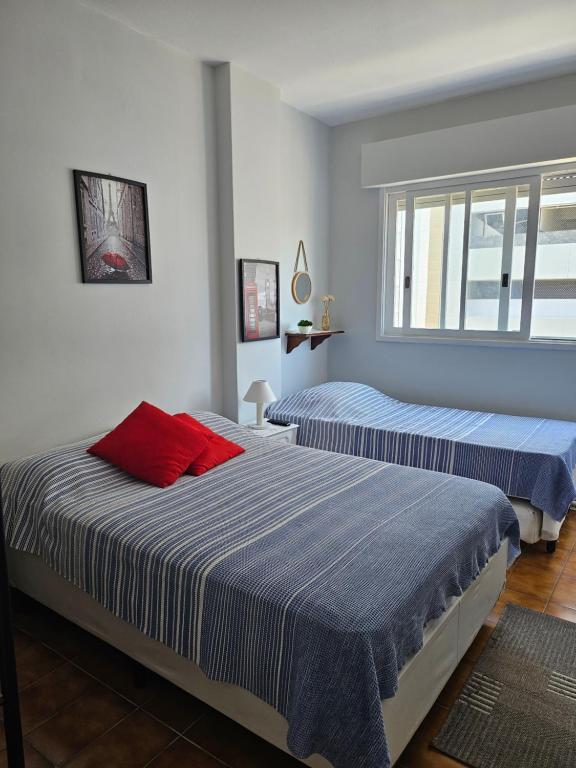Apartamentos na Praia do Gonzaga في سانتوس: غرفة نوم بسريرين مع وسائد زرقاء وحمراء