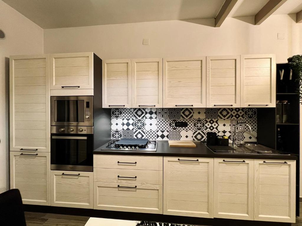 una cucina con armadi bianchi e piastrelle bianche e nere di Il nido del Viaggiatore a San Giorgio Ionico