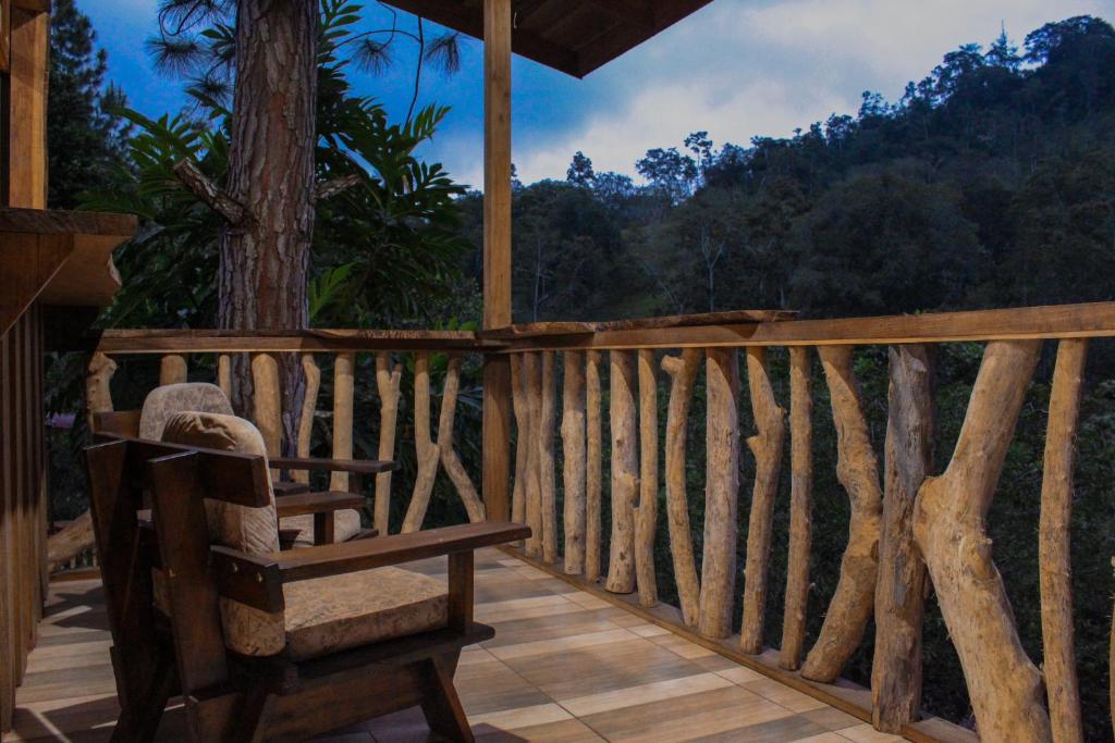 a rocking chair on a porch with a view of the forest at Finca La Unión in Turrialba