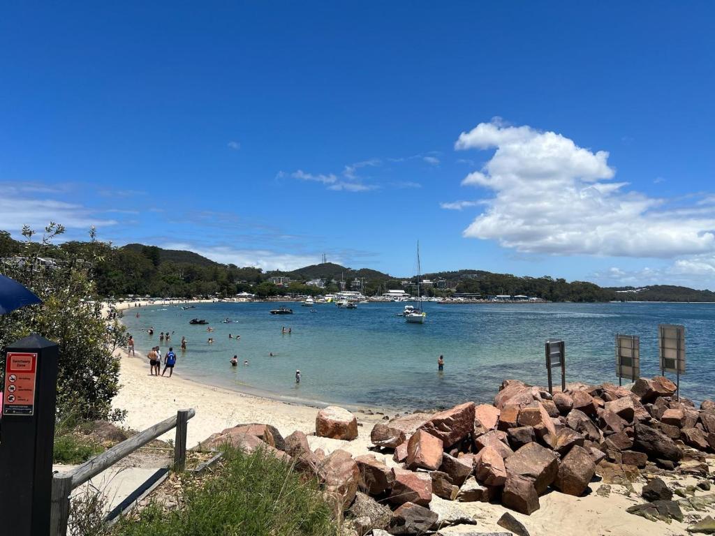 a group of people in the water at a beach at Foreshore Paradise Nelson Bay in Nelson Bay