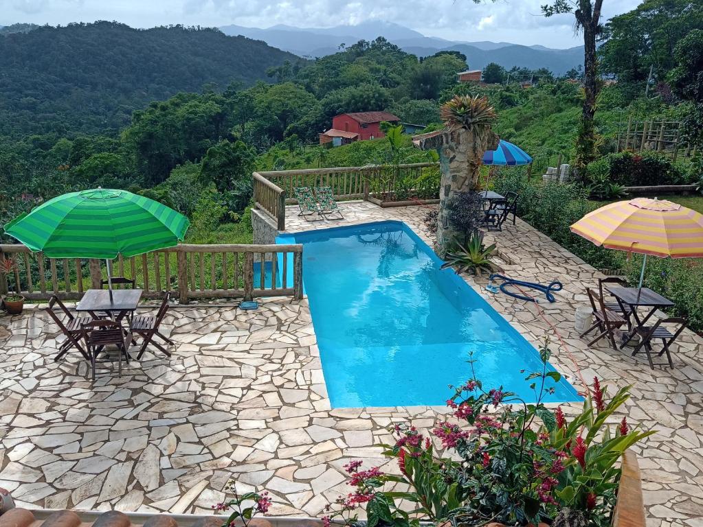 a swimming pool with two umbrellas and tables and chairs at Recanto bela Vista caminho do ouro in Paraty