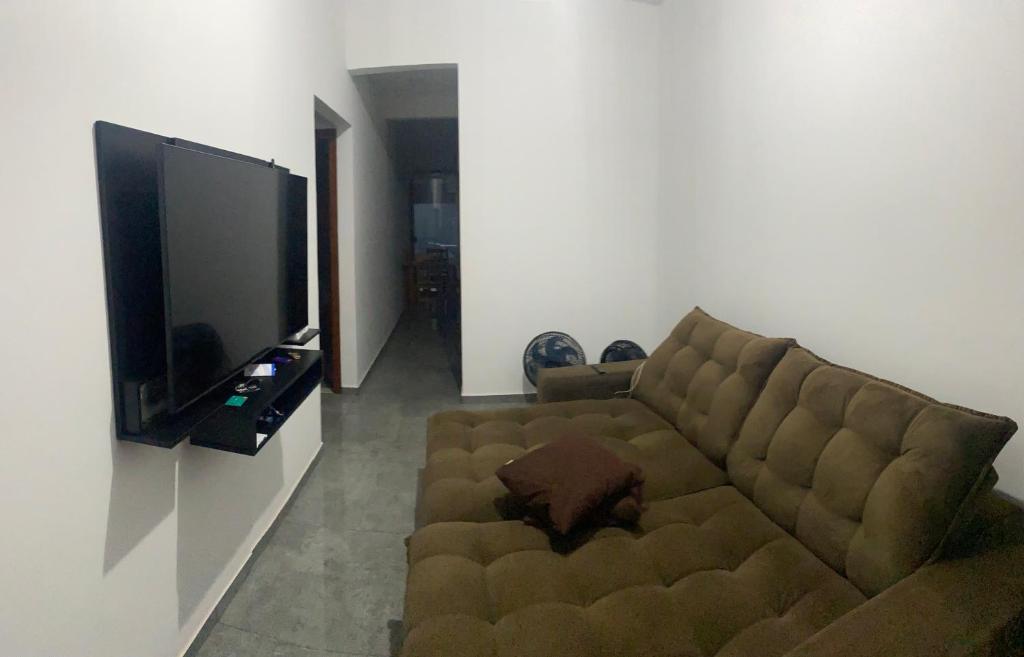 uma sala de estar com um sofá castanho e uma televisão de ecrã plano em Casa - Temporada Show rural em Cascavel