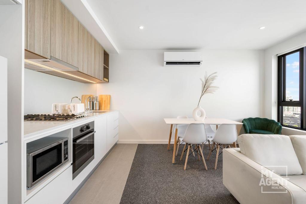 een witte keuken met een bank en een tafel bij 2 Bedroom Apartment in Southbanks Stature Building in Melbourne