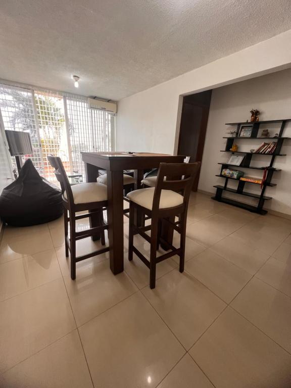 Catia La Mar的住宿－Apartamento Aeropuerto Maiquetia en Planta Baja，一间带木桌和椅子的用餐室