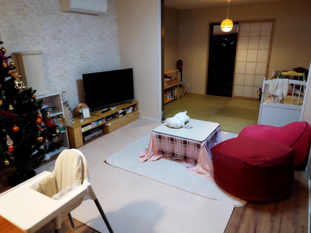 una sala de estar con un árbol de Navidad y un sofá y una mesa en IIIホーム en Shijonawate