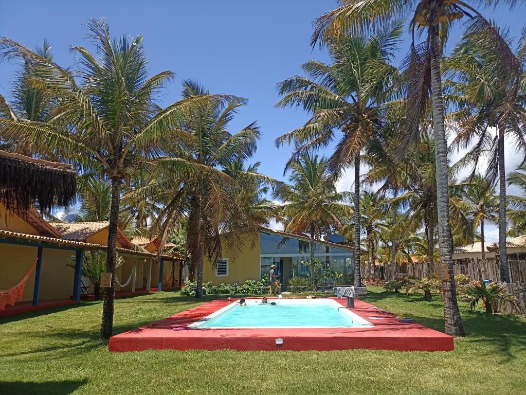 a swimming pool in a yard with palm trees at Pousada Flor de Elisa frente a praia in Caraíva