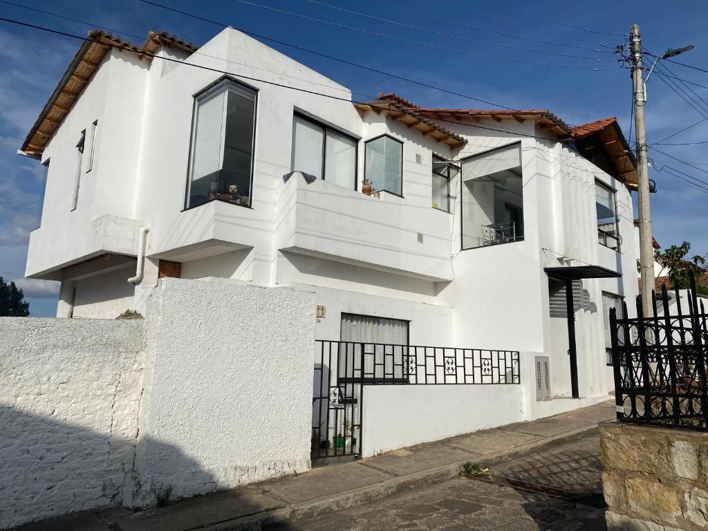 une maison blanche avec une clôture devant elle dans l'établissement Apartamento 202, à Guatavita