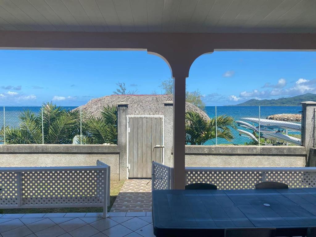 a view of the ocean from a patio with a table and benches at Vaiana Home 2 - bord de lagon in Taputapuapea