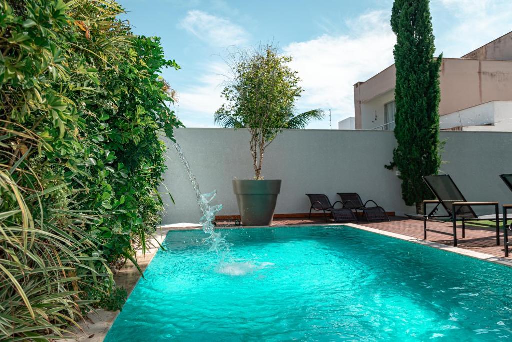 a swimming pool with a fountain in a yard at Casa de Temporada Homer House in Porto Seguro