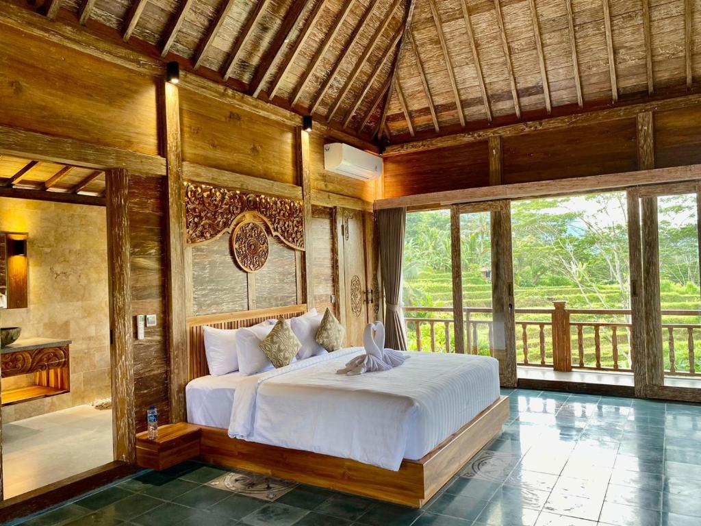 a bedroom with a bed in a room with windows at Abian Ayu Villa in Sidemen