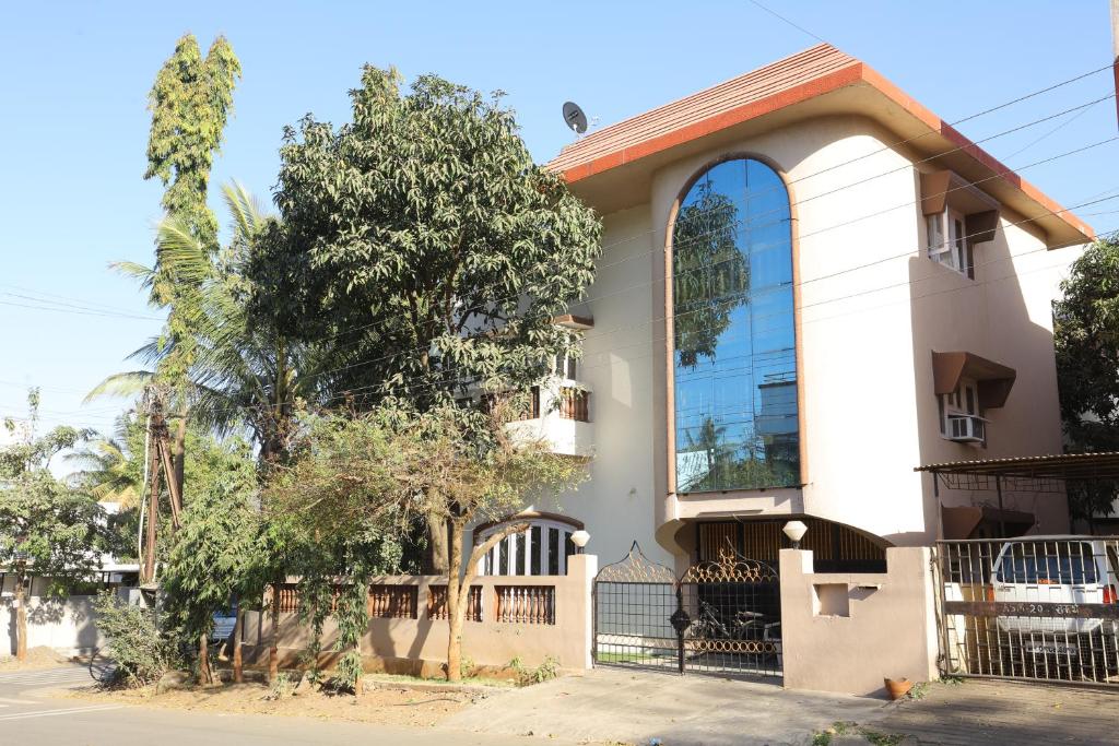 a white house with a gate and a tree at ROHAN HOUSE in Nashik