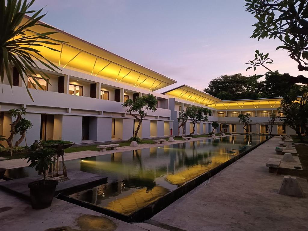 a hotel with a pool in front of a building at Guna Graha Kuta by Kamara in Kuta