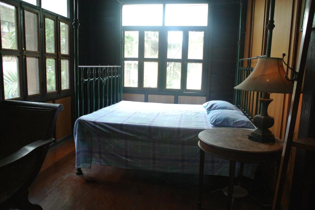 a bedroom with a bed and a table with a lamp at Villa Guest House in Bangkok