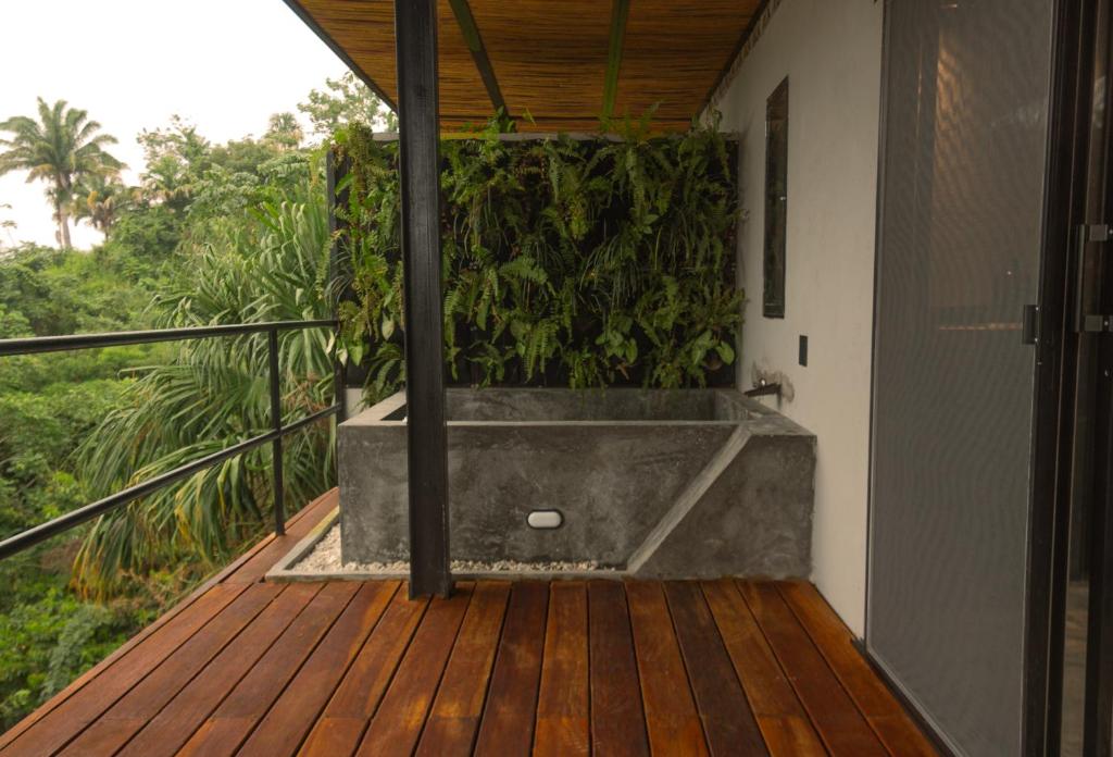 a bathtub on a deck with a green wall at Alma Tayrona Lodge in Los Naranjos