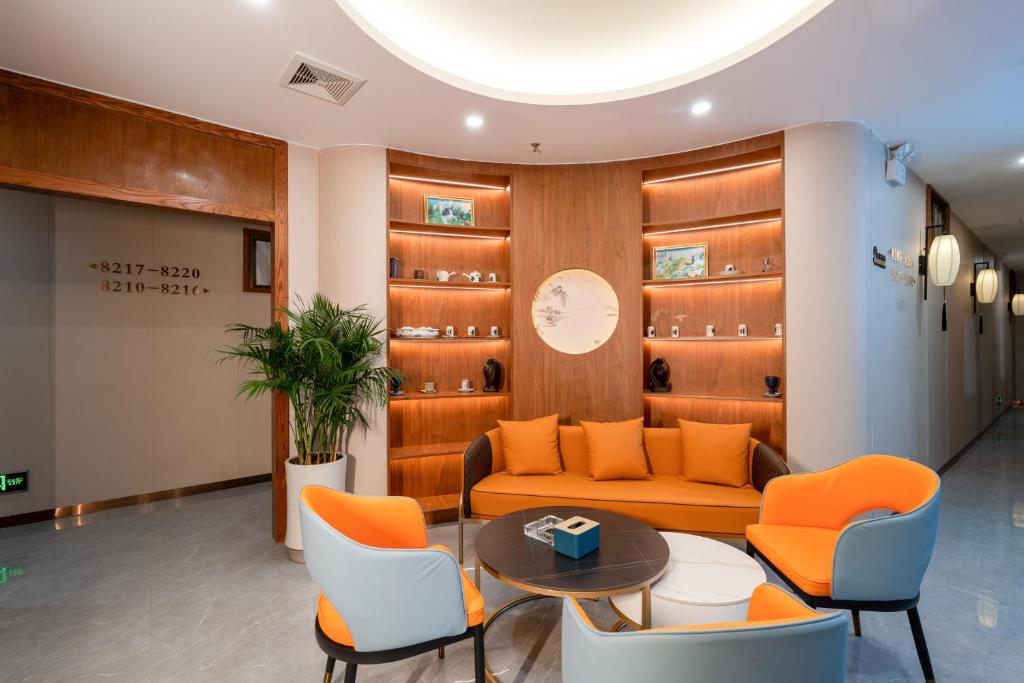 a waiting room with an orange couch and chairs at Shengda Hotel Zhuhai in Zhuhai