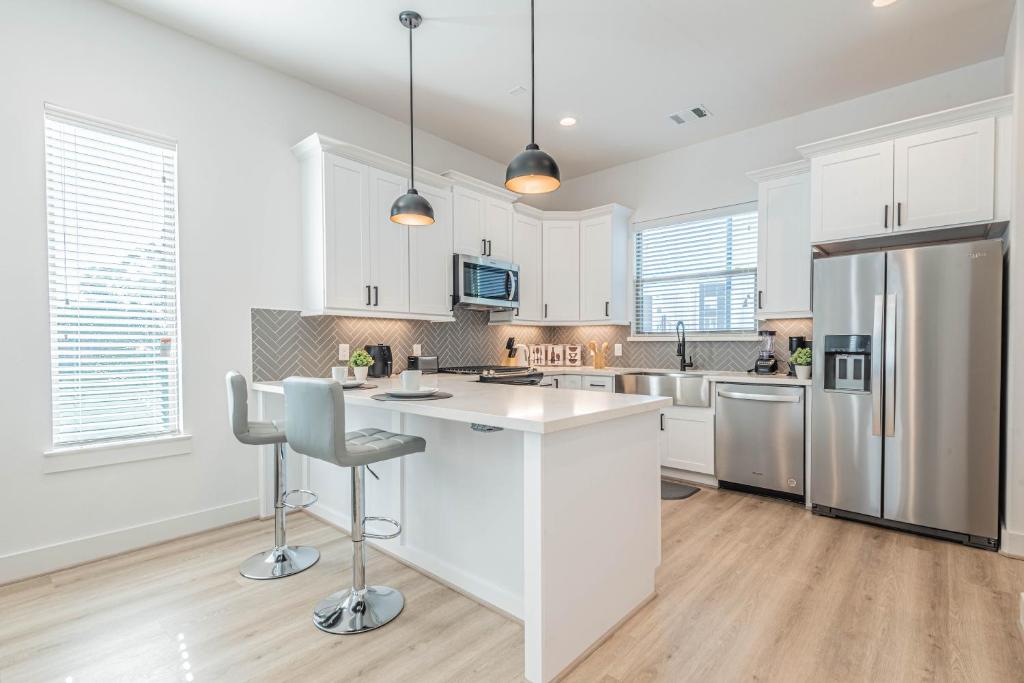 a kitchen with white cabinets and a stainless steel refrigerator at Luxury Charming 3BR 3Bath Free Wi-FI 8 Guests, Gated Home, Houston Downtown in Houston