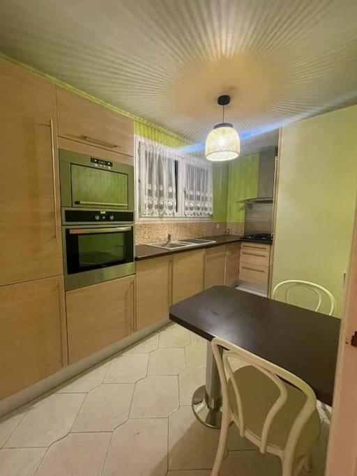 eine Küche mit einem Tisch und einem Herd Top-Backofen in der Unterkunft Appartement JO 2024 Paris Disney in Villeparisis