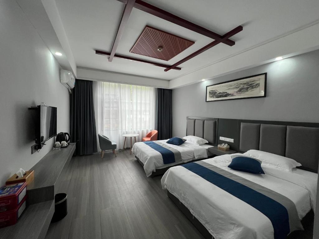 um quarto de hotel com duas camas e uma televisão em 张家界喜见客栈 em Zhangjiajie