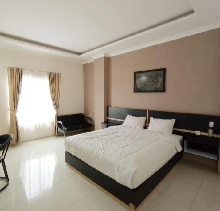 una camera con un grande letto e una finestra di KHARIZ HOTEL a Bukittinggi