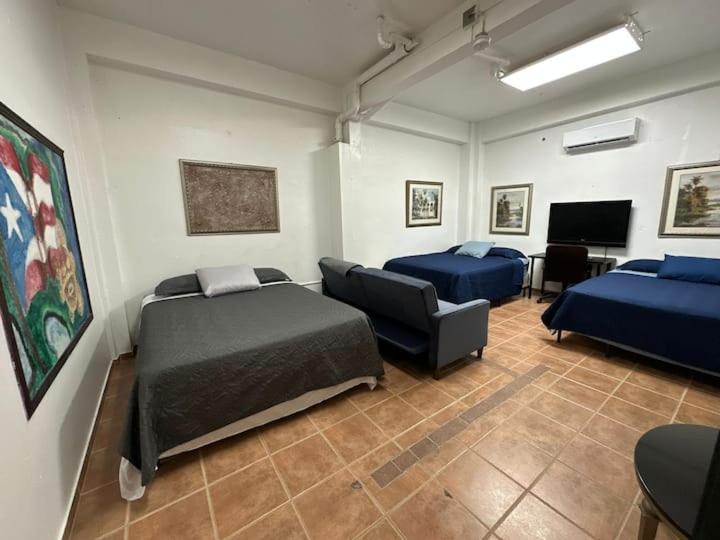 Zimmer mit 2 Betten, einem Sofa und einem TV in der Unterkunft Newly remodeled 3 BR Center Mayagüez, First Floor Unit1 in Mayaguez