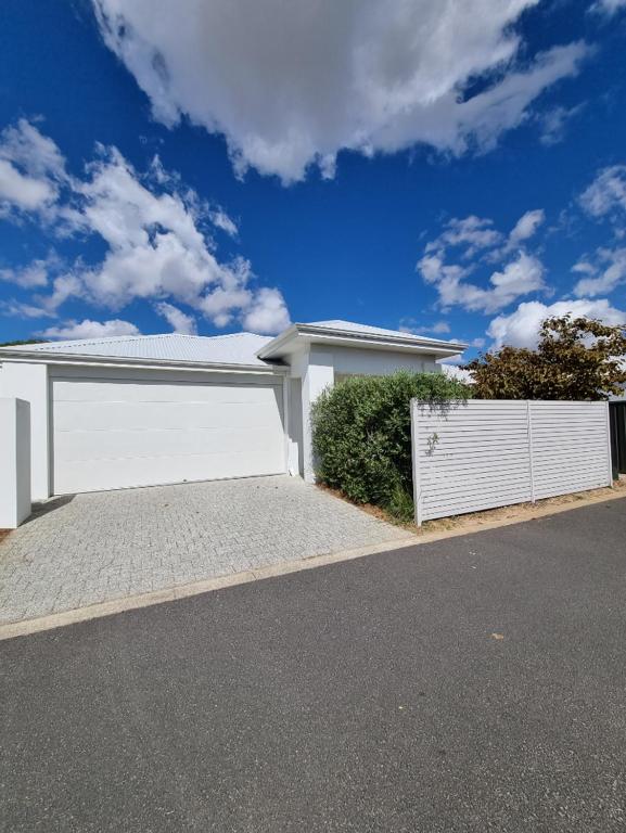 un garage blanc avec une clôture blanche dans une rue dans l'établissement The White House, à Geographe